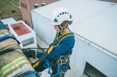 Latin itfaiyeci bir binadan iple inmek üzere.