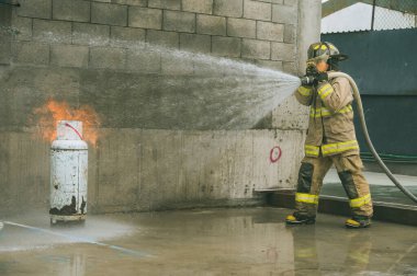 İtfaiyeci, bir gaz tankını söndürmek için yangın hortumuyla su perdesi oluşturuyor.