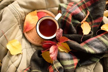 Sonbahar havası, düşünme, park konseptinde piknikte dinlenme. Renkli yaprakların arka planına karşı sıcak çayı olan güzel bir kupa yorganın mantar tepsisinin üzerinde duruyor. Sıcak renkler. Üst görünüm.