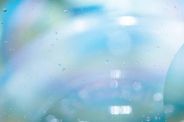Suyun soyut mavi arkaplanı, damlalar, yansımalar, parlaklık. Su, yağmur, su daireleri teması. Yatay olarak. Yumuşak odak.