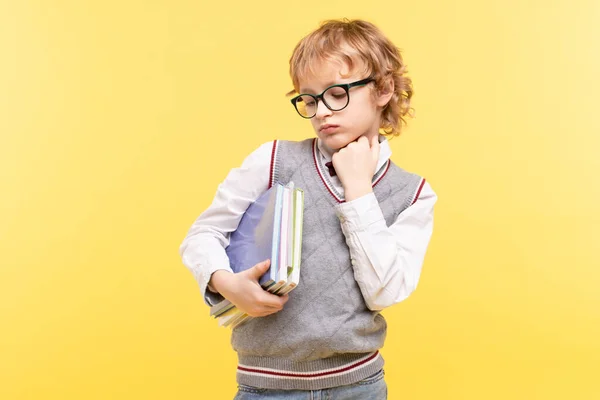 眼鏡をかけた疲れた少年は悲しいことに手元の教科書を見ています ブロンド 黄色のスタジオの背景 学習問題の概念は 学校では 学校に戻る退屈 スペースのコピー — ストック写真