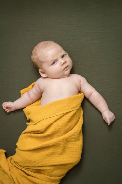 Güzel, tombul, yeni doğmuş bir bebek, modaya uygun sarı bir çarşafa sarılmış. Uyandım ve sana bakarak yalan söyledim. Güzel manzara. Yaşam tarzı. Kafkasyalı. Ebeveynliğin mutluluğu, annelik, bebek bakımı konsepti..