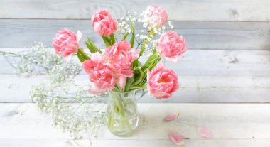 Beyaz tahtaların arka planında vazoda duran güzel pembe laleler. Bahar buketi kavramı, 8 Mart, kadınlar günü, ilkbahar, şenlik havası, anneler günü, bayram, mutlu yıllar. Hiç kimse. Yatay.