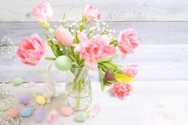 Güzel pembe laleler, dekoratif paskalya yumurtaları, tavşancık, arka planda çikolata yumurtası. Şık Paskalya dekoru, yumurta saklama geleneği, bahar zamanı, şenlik havası. Yatay.