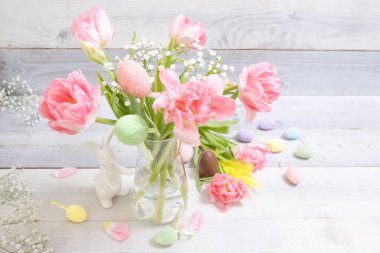 Güzel pembe laleler, dekoratif paskalya yumurtaları, tavşancık, arka planda çikolata yumurtası. Şık Paskalya dekoru, yumurta saklama geleneği, bahar zamanı, şenlik havası. Yatay.