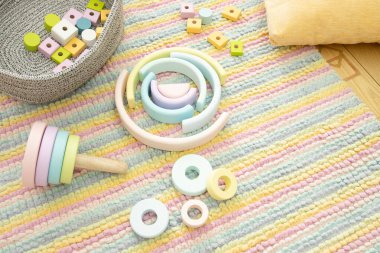 Modern ahşap oyuncaklar - piramit ve gökkuşağı çocukların odasındaki çizgili halıya saçılmış. Dağınıklık kavramı, temizlik, çevre dostu malzemelerden alınan oyuncaklar, bebeğin gelişimi için oyuncaklar, oyun odasında düzen..