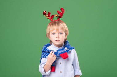 Kafkas sarışının portresi, güzel saçlı aksesuarlı Noel geyiği boynuzları ve boynunda kış mavisi süveteri. Stüdyo yeşil arka plan. Noel, yeni yıl konsepti.