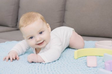 Sevimli yeni doğmuş bebek kanepede el yapımı örgü halıda yatıyor. Başını iyi tutuyor. Duygusal bir yüz. Beyaz bir çocuk. Annelik, güzel bebekler, ev kavramı. Yaşam biçimi.