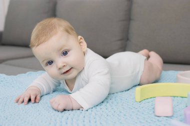 Sevimli yeni doğmuş bebek kanepede el yapımı örgü halıda yatıyor. Başını iyi tutuyor. Duygusal bir yüz. Beyaz bir çocuk. Annelik, güzel bebekler, ev kavramı. Yaşam biçimi.