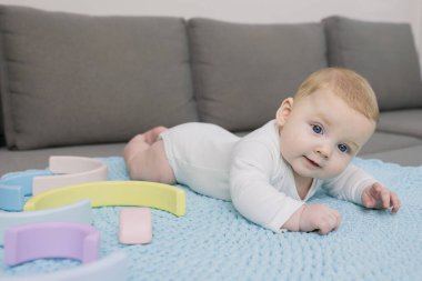 Sevimli yeni doğmuş bebek kanepede el yapımı örgü halıda yatıyor. Başını iyi tutuyor. Duygusal bir yüz. Beyaz bir çocuk. Annelik, güzel bebekler, ev kavramı. Yaşam biçimi.