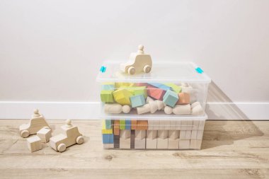 Tahta küpler, plastik kaplarda sıralanmış çocuk oyuncakları, çocuk odasının zemininde durmak. Ekolojik malzemelerden oyuncak yapma, evi düzenleme, düzenleme ve düzenleme kavramı.. 