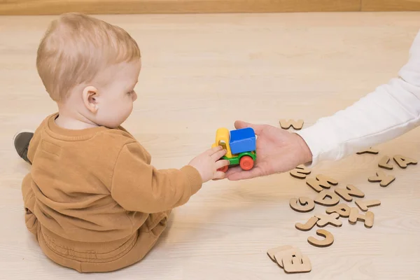 Baby Boy Takes Toy Car Hands Dad Sitting Wooden Floor — Stock Photo, Image