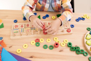 Çocuk matematik gelişimi, öğrenim merkezi, ilkokul, sınıflandırma becerileri, Montessori. Ahşap bir matematik oyuncağıyla oynayan beyaz bir çocuğun elleri. Sayı çizgisi, sayıyor. Üst Manzara. Yaşam biçimi.
