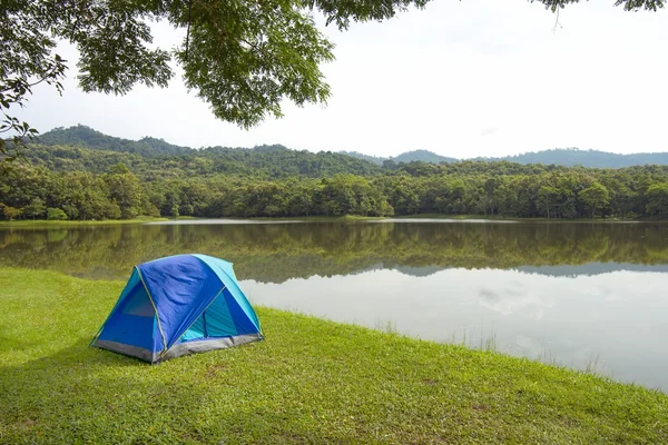 Une tente sur l'herbe verte près d'un lac — Photo