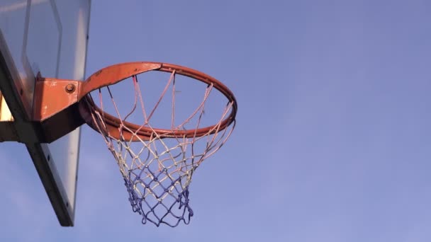 Мяч летит в баскетбольное кольцо на фоне облаков. — стоковое видео