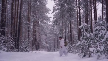 Kış ormanında köpekli bir insan avcısı. Silahlı bir avcı orman yolunda yürüyor.