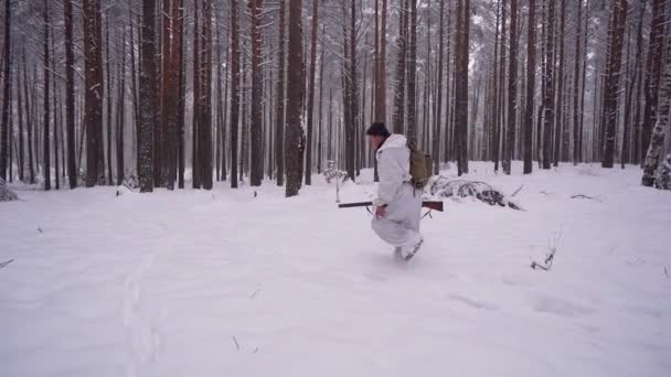 Un cacciatore maschio cammina attraverso la foresta invernale e indica al cane il sentiero di un animale selvatico.. — Video Stock