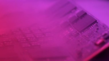 Duman devre kartının üzerine dağılır. Elektronik Cihazın İçinde Bileşenlerle Yazdırılmış Devre Panosu. Neon Renkleri. Renk değişir ve ışık parlar..