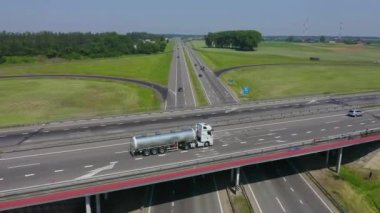 Kamyon köprüde gidiyor ve yol boyunca ilerlemeye devam ediyor. Kamyon köprü boyunca gidiyor, aşağıdan diğer kamyonların geçtiği yoldan geçiyor. Hava görünümü.