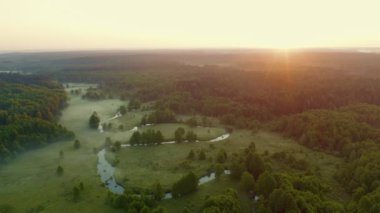 Hava aracı, kıvrımlı nehrin üzerinden uçarak yeşil çayır ve ormandan geçer. Su yüzeyinde sis, sabahın erken saatlerinde. Güneş doğmadan önce suyun üzerinde uçuyor. Puslu şafak, cennet gibi yeşil vadi