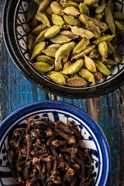 Cardamom and cloves in bowls — Stock Photo, Image