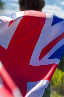 Büyük Britanya bayrağı genç bir adamın elinde. Yakın çekim, seçici odaklanma.