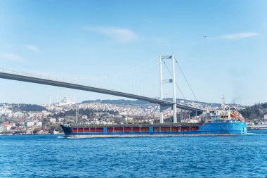 İstanbul Boğazı 'ndan geçen Şehitler Köprüsü, 15 Temmuz' da. Mavna Boğaz boyunca yelken açar. Boğaz köprüsü ve konteynırlı kargo gemisi.