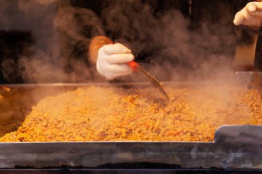 Roasting the filling for the traditional Turkish fast food kokorech. Cooking kokorech in Istanbul. Cook's hand with a spatula near a frying pan in Turkey clipart