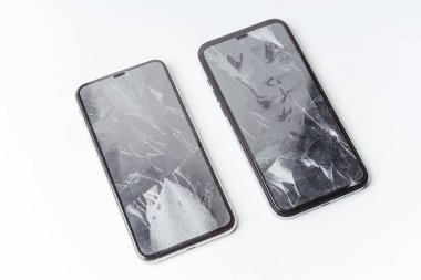 Beyaz arka planda iki tane kırık akıllı telefon. Akıllı telefon için koruyucu camı kırın. Ekranı kırık bir akıllı telefon. Çatlak ön telefon ekran koruyucusu filmi