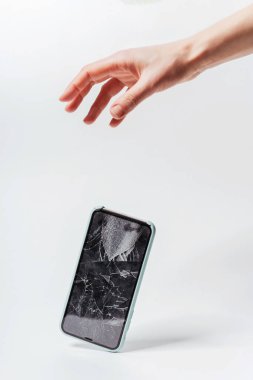 Beyaz arka planda akıllı telefonun elinden düşmesi. Akıllı telefon için koruyucu camı kırın. Bozuk ekranlı akıllı telefon kontrolden çıktı.