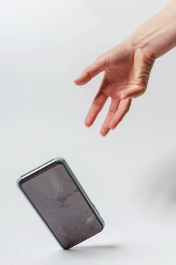 Beyaz arka planda akıllı telefonun elinden düşmesi. Akıllı telefon için koruyucu camı kırın. Bozuk ekranlı akıllı telefon kontrolden çıktı.