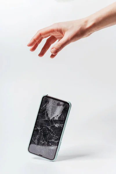 Beyaz arka planda akıllı telefonun elinden düşmesi. Akıllı telefon için koruyucu camı kırın. Bozuk ekranlı akıllı telefon kontrolden çıktı.