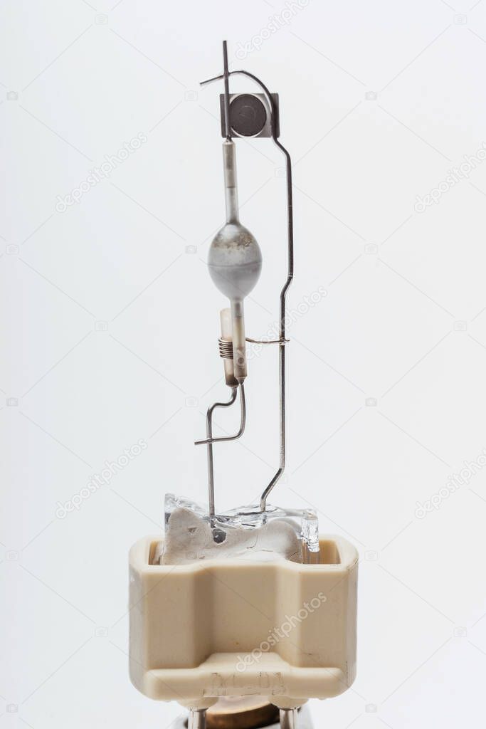 A broken halogen lamp on a white background. A discharge tube in a broken incandescent light bulb. Light Bulb details close-up