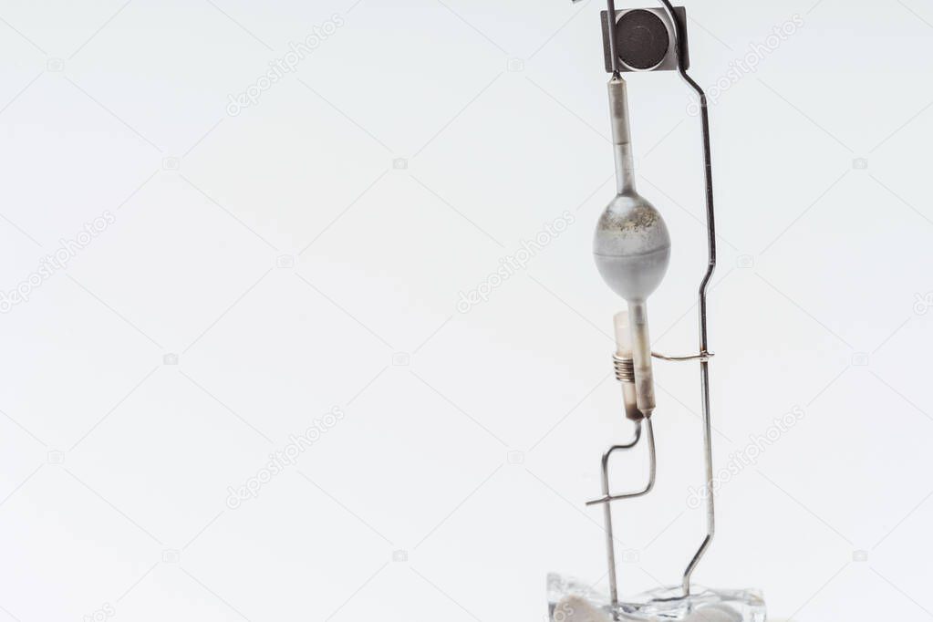 A broken halogen lamp on a white background. A discharge tube in a broken incandescent light bulb. Light Bulb details close-up