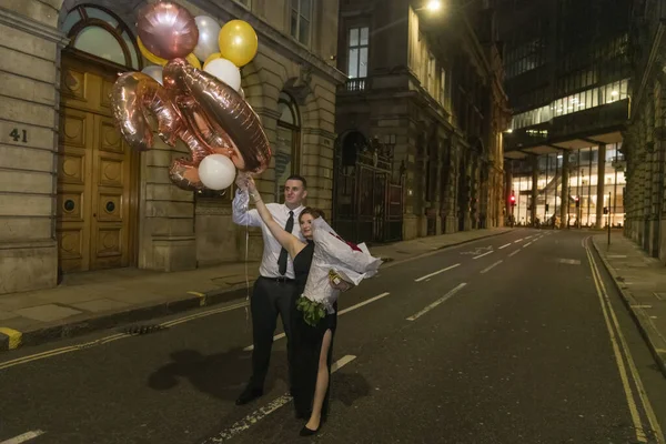 Braut und Bräutigam mit Brautstrauß und Luftballons — Stockfoto