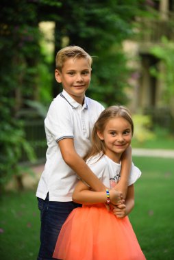 Erkek ve kız kardeş gün batımında parkta çimlerin üzerinde koşar, oynar ve eğlenirler. Mutlu çocukluk.