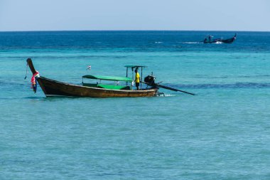 Tayland adası kıyısı yakınlarındaki turkuaz tropikal denizde geleneksel uzun kuyruklu tekne. Egzotik suyla okyanus manzarası, yaz tatili, deniz kültürü ve macera gezisi. Turizm, tatil ve doğa konsepti için mükemmel deniz manzarası.
