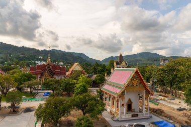 Büyüleyici bir tapınak, yemyeşil ve görkemli dağların arasında, bulutlu bir gökyüzünün altında.