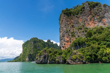 Açık mavi gökyüzünün altında nefes kesici, gür, canlı, yeşil uçurumlar ve sakin suları gösteren bir manzara