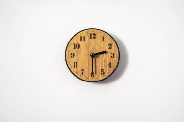 Beyaz zemin üzerinde beyaz kadranlı ahşap ofis duvar saati. Beyaz arkaplanda duvar saati, en üst görünüm.