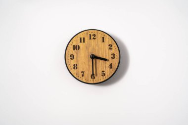 Beyaz zemin üzerinde beyaz kadranlı ahşap ofis duvar saati. Beyaz arkaplanda duvar saati, en üst görünüm.
