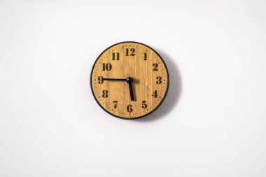 Beyaz zemin üzerinde beyaz kadranlı ahşap ofis duvar saati. Beyaz arkaplanda duvar saati, en üst görünüm.