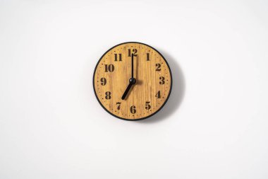 Beyaz zemin üzerinde beyaz kadranlı ahşap ofis duvar saati. Beyaz arkaplanda duvar saati, en üst görünüm.