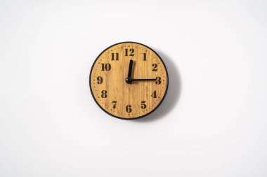 Beyaz zemin üzerinde beyaz kadranlı ahşap ofis duvar saati. Beyaz arkaplanda duvar saati, en üst görünüm.