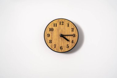 Beyaz zemin üzerinde beyaz kadranlı ahşap ofis duvar saati. Beyaz arkaplanda duvar saati, en üst görünüm.