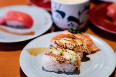 Suşi ve Sashimi. Suşi ve Sashimi tabakları taşıma bandında yuvarlanıyor..