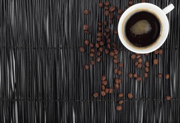 Кофейная чашка с кофейными зернами на черном фоне — стоковое фото