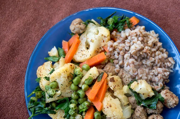 Buckwheat porridge and vegetables. Cauliflower and carrots. Steamed meatballs and vegetables. Vegetable stew with herbs. Diet food. A mixture of boiled vegetables