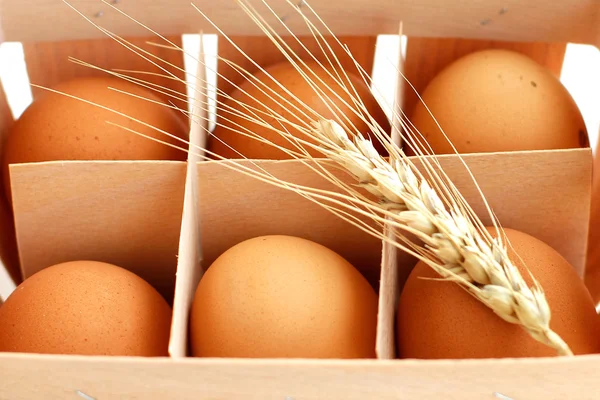 Eggs with ear of wheat in wicker basket — Stock Photo, Image