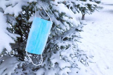 Blue medical protective face mask hanging on christmas tree branch. Social Issues - pandemic coronavirus. Blue medical mask christmas tree decoration, pandemic, coronavirus, COVID-19 clipart